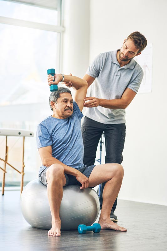 a physical therapist works with a hispanic man on upper extremity exercise for shoulder and elbow pain